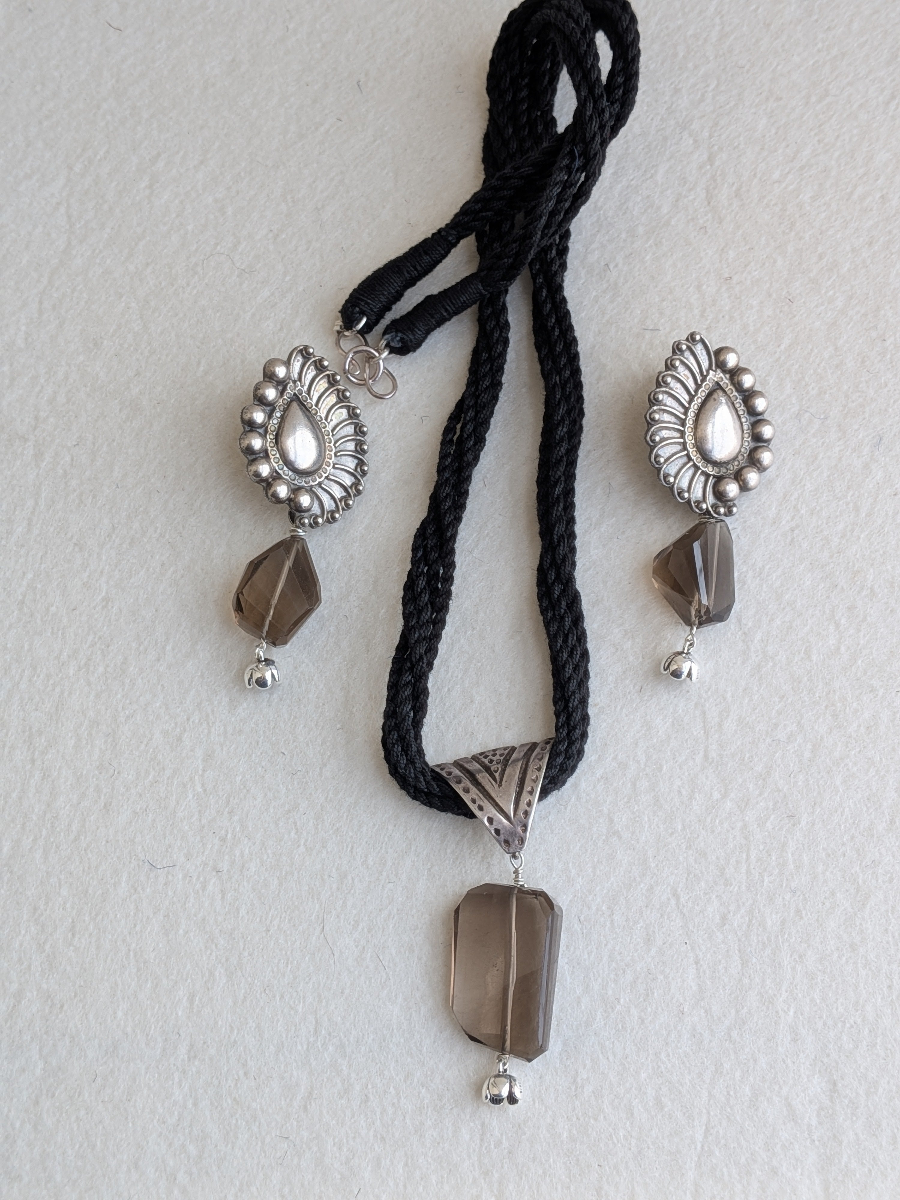 Handcrafted 925 silver jewelry set with triangle pendant and peacock feather earrings, adorned with smokey quartz. Perfect for weddings and festivals