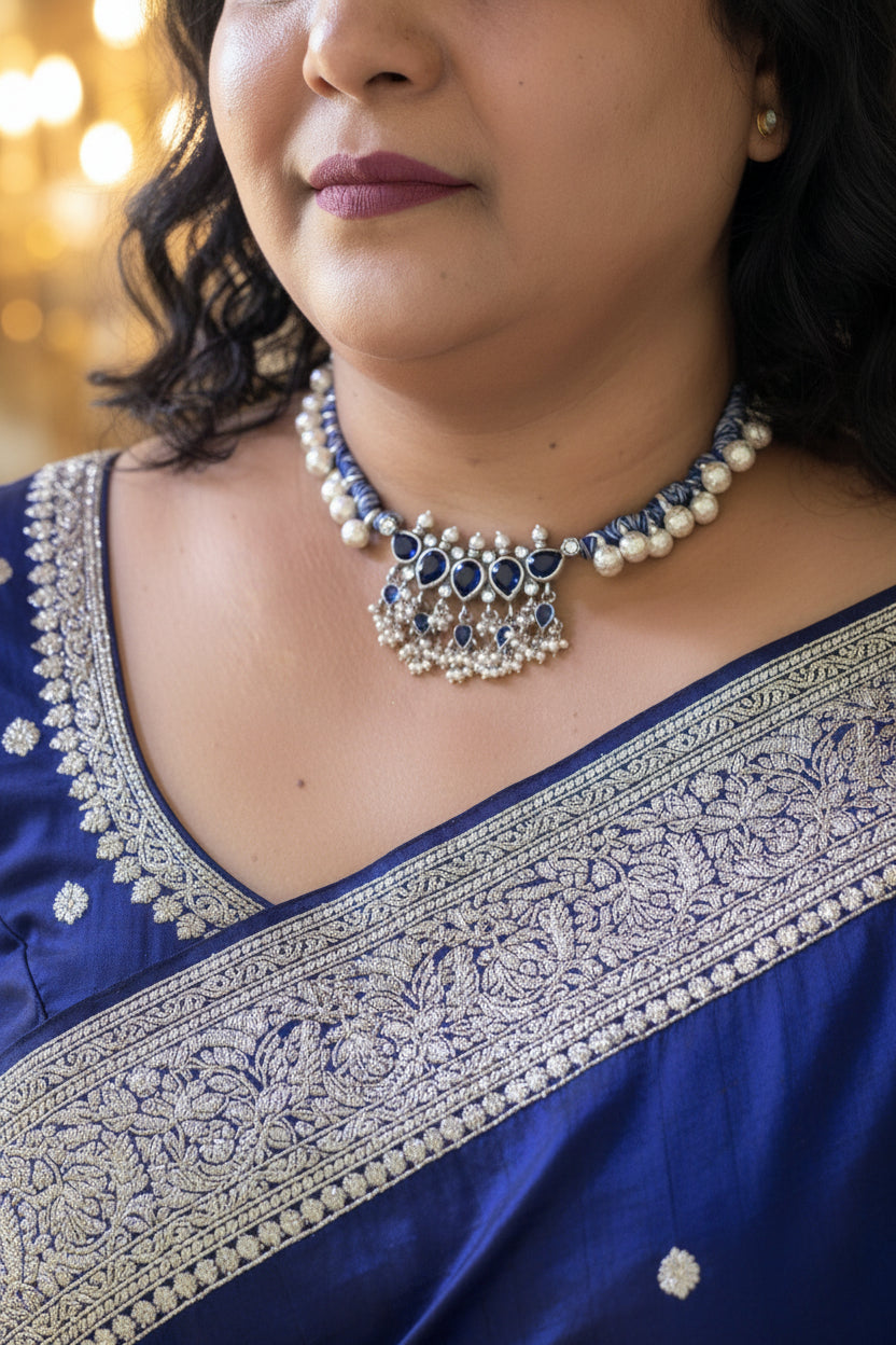 Close-up of a person wearing a detailed necklace with blue and white elements.