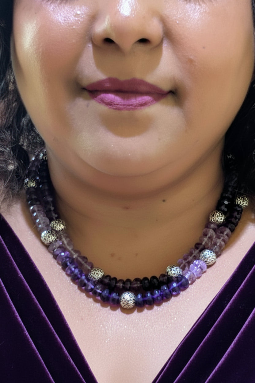 Close-up of a person wearing a beaded necklace with purple and gold beads.